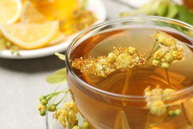 Photo of Cup of tea with linden blossom on table, closeup