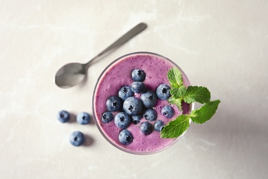 Photo of Glass with blueberry smoothie on light background, top view