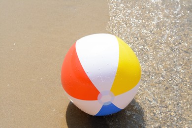 Photo of Colorful beach ball on wet sand at seaside