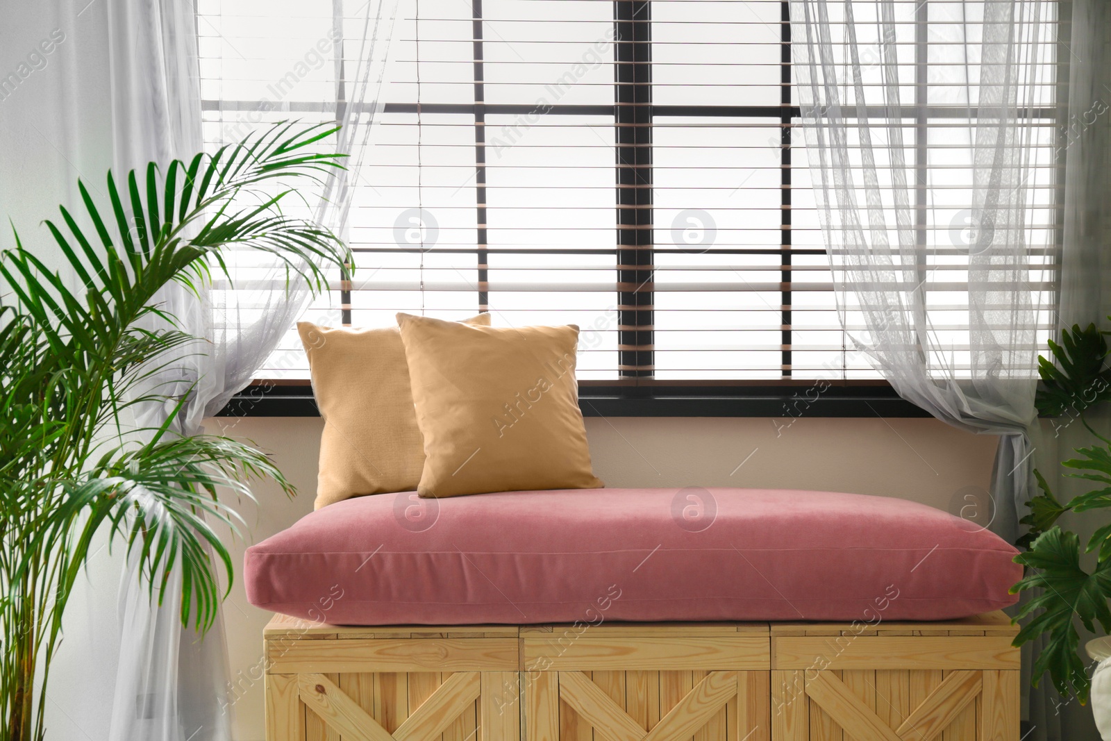 Photo of Bench made of wooden crates and pillows near window in room. Interior design