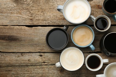 Photo of Different coffee drinks in cups on wooden table, flat lay. Space for text