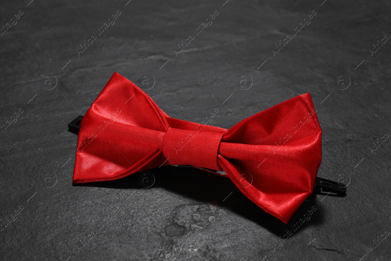 Photo of Stylish red bow tie on black table, closeup