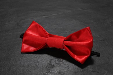 Stylish red bow tie on black table, closeup