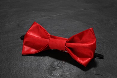 Photo of Stylish red bow tie on black table, closeup