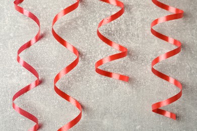 Photo of Shiny red serpentine streamers on grey background, flat lay