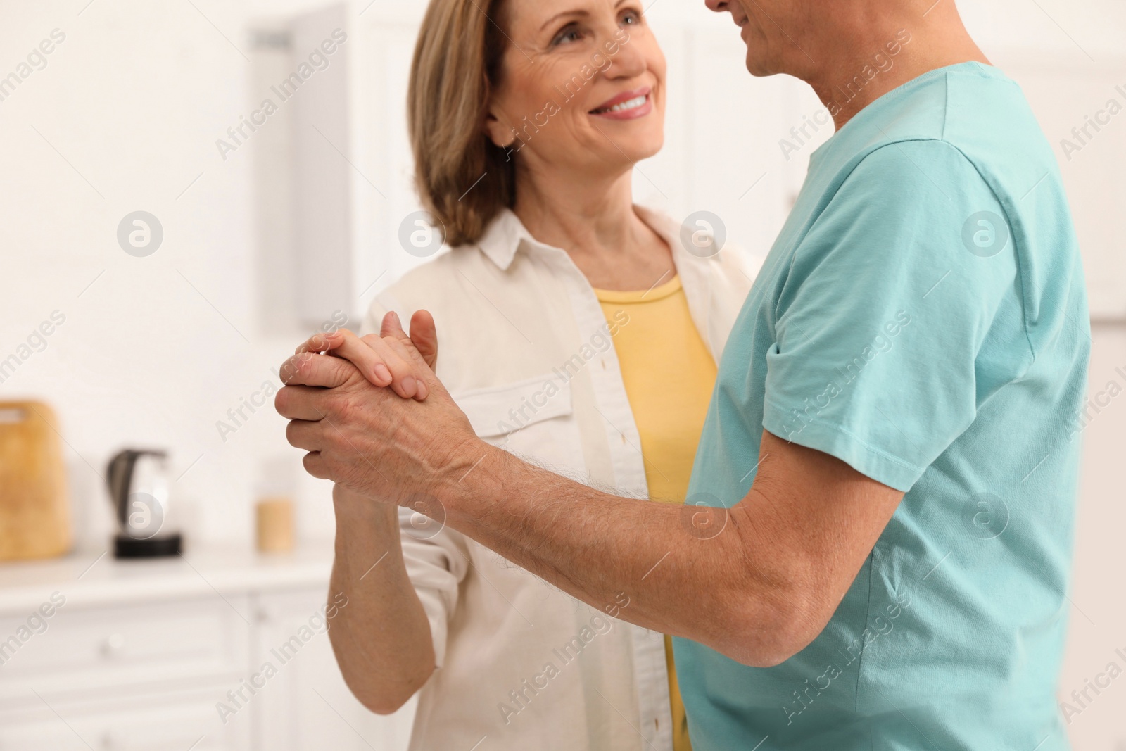 Photo of Happy senior couple dancing in kitchen, closeup