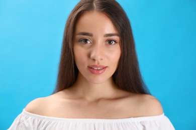 Photo of Portrait of beautiful young woman on light blue background, closeup
