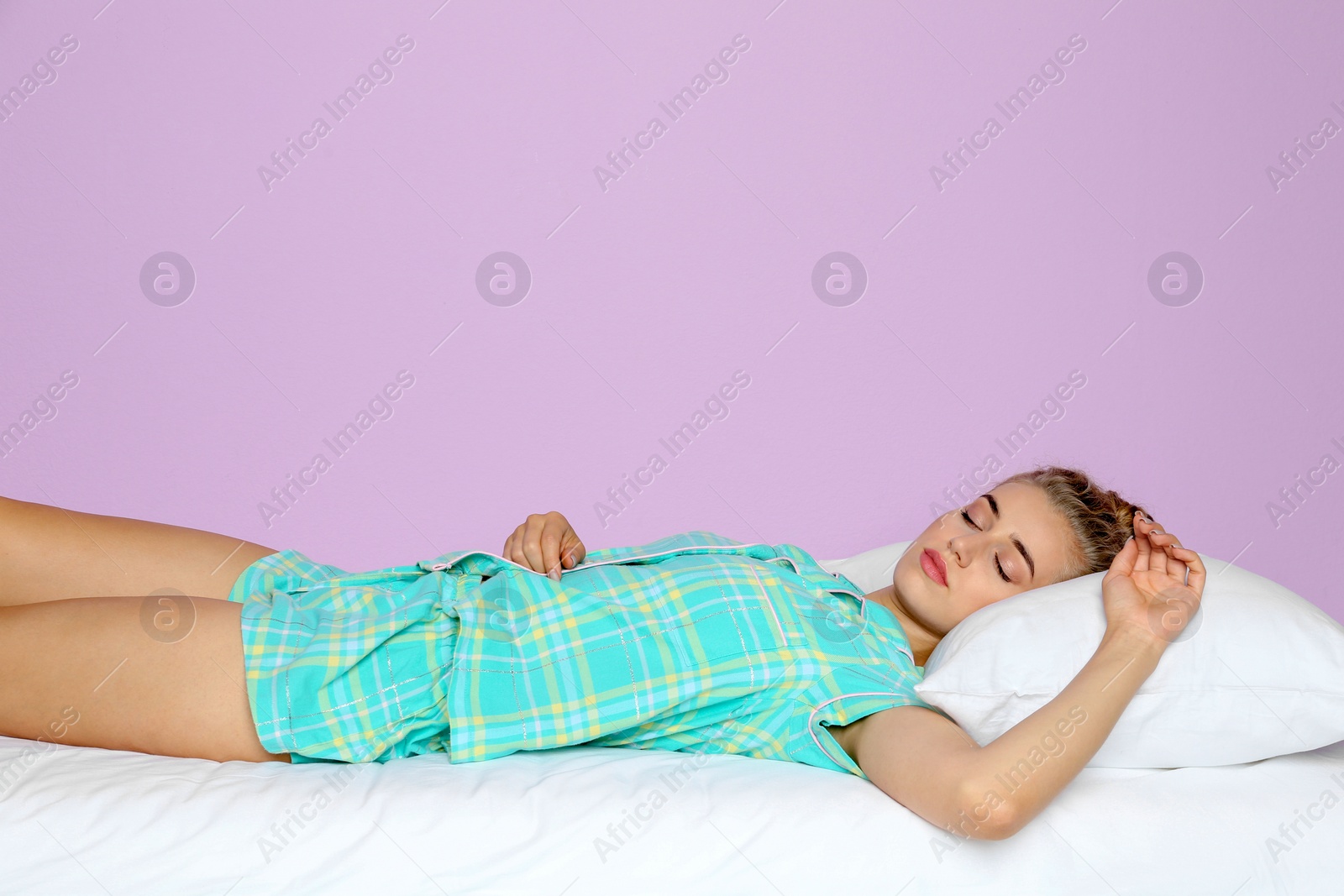 Photo of Beautiful woman sleeping with comfortable pillow on bed against color background