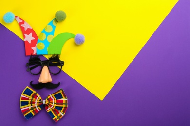 Photo of Flat lay composition clown's face made of party glasses, hat and bow tie on color background. Space for text