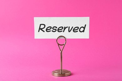 Photo of Elegant sign Reserved on pink background. Table setting element
