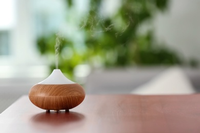 Aroma oil diffuser lamp on table against blurred background