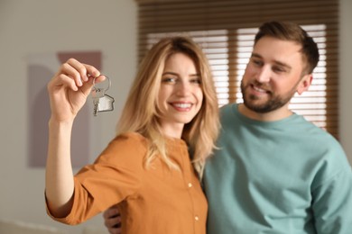 Photo of Happy young couple with key in new house, focus on hand