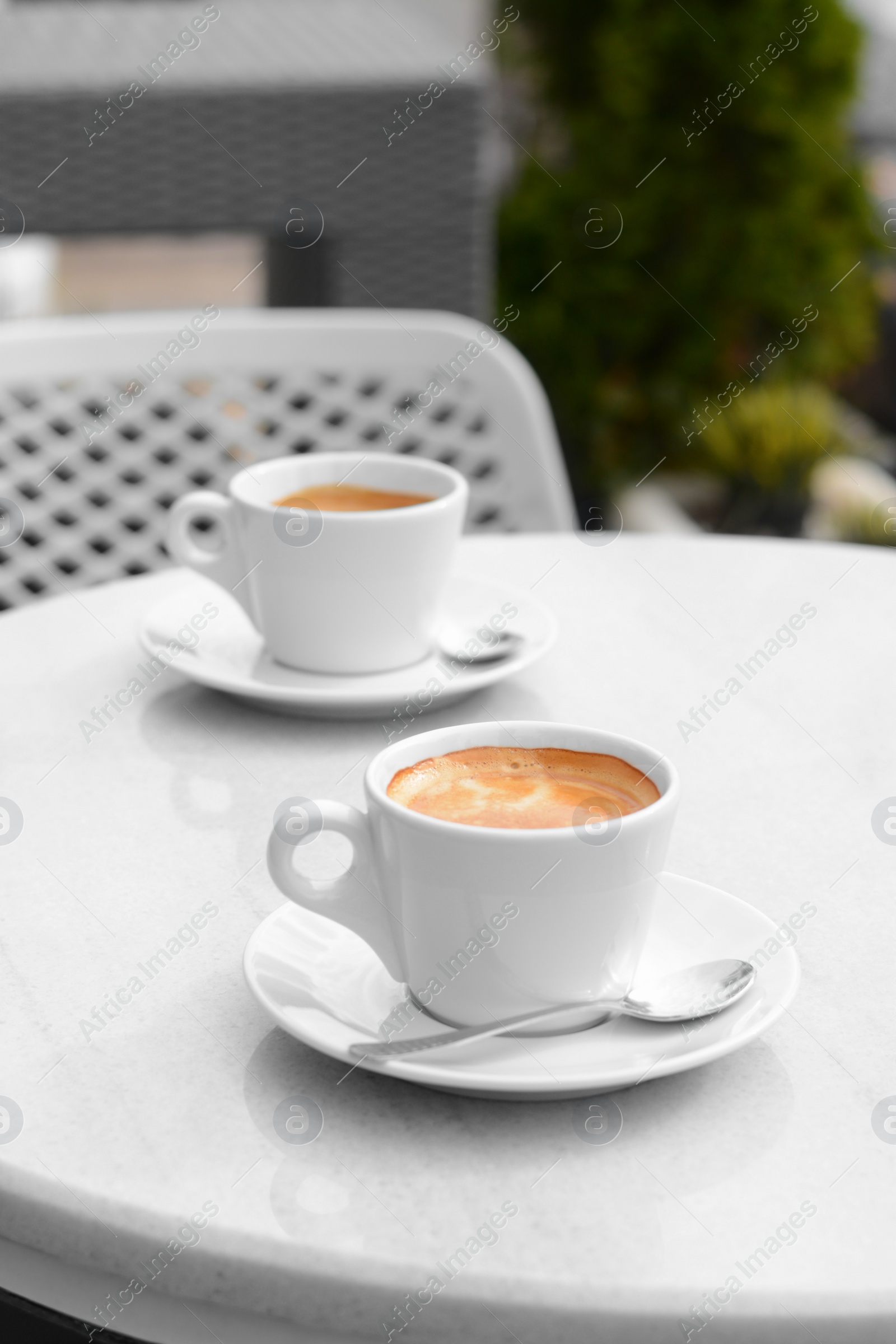 Photo of Ceramic cups of aromatic coffee with foam on table in morning