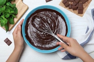 Woman making delicious chocolate cream at white wooden table, top view