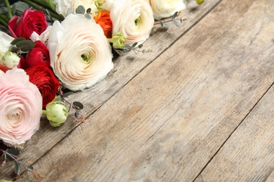 Beautiful ranunculus flowers and space for text on wooden background