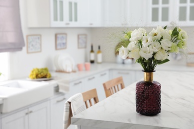 Bouquet of beautiful eustoma flowers on white table in kitchen. Interior design