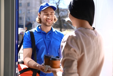 Photo of Woman receiving order from courier at door. Food delivery service