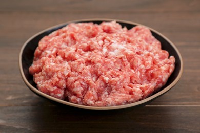 Photo of Bowl with raw fresh minced meat on wooden table, closeup