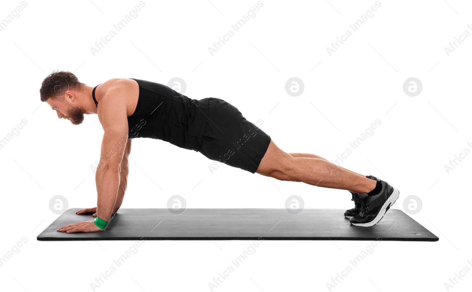 Photo of Young man exercising with elastic resistance band on fitness mat against white background