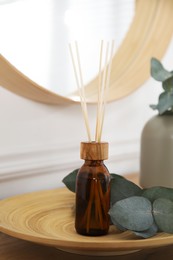 Photo of Reed diffuser and home decor on wooden table near white wall