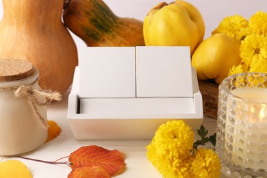 Photo of Thanksgiving day, holiday celebrated every fourth Thursday in November. Block calendar, candle, pumpkins, quinces and chrysanthemum flowers on white wooden table