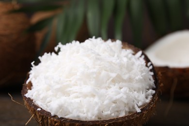 Photo of Coconut flakes in nut shell on table, closeup