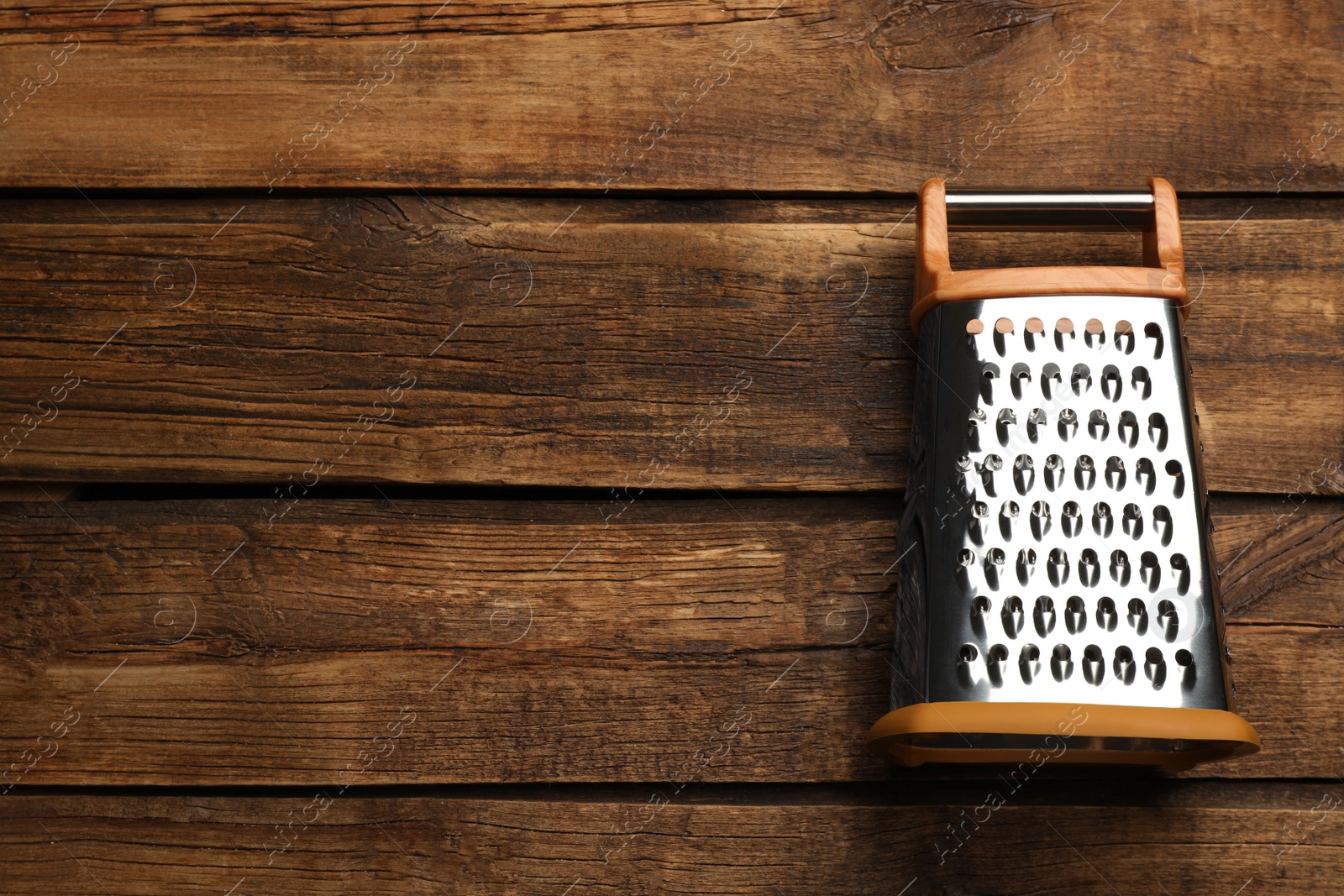 Photo of Modern grater on wooden table, top view. Space for text