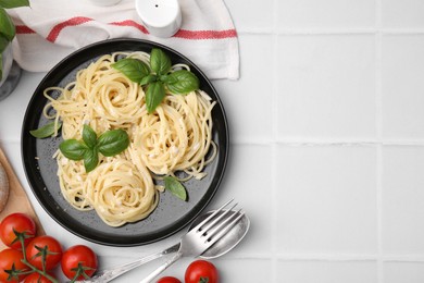 Photo of Delicious pasta with brie cheese and products served on white tiled table, flat lay. Space for text