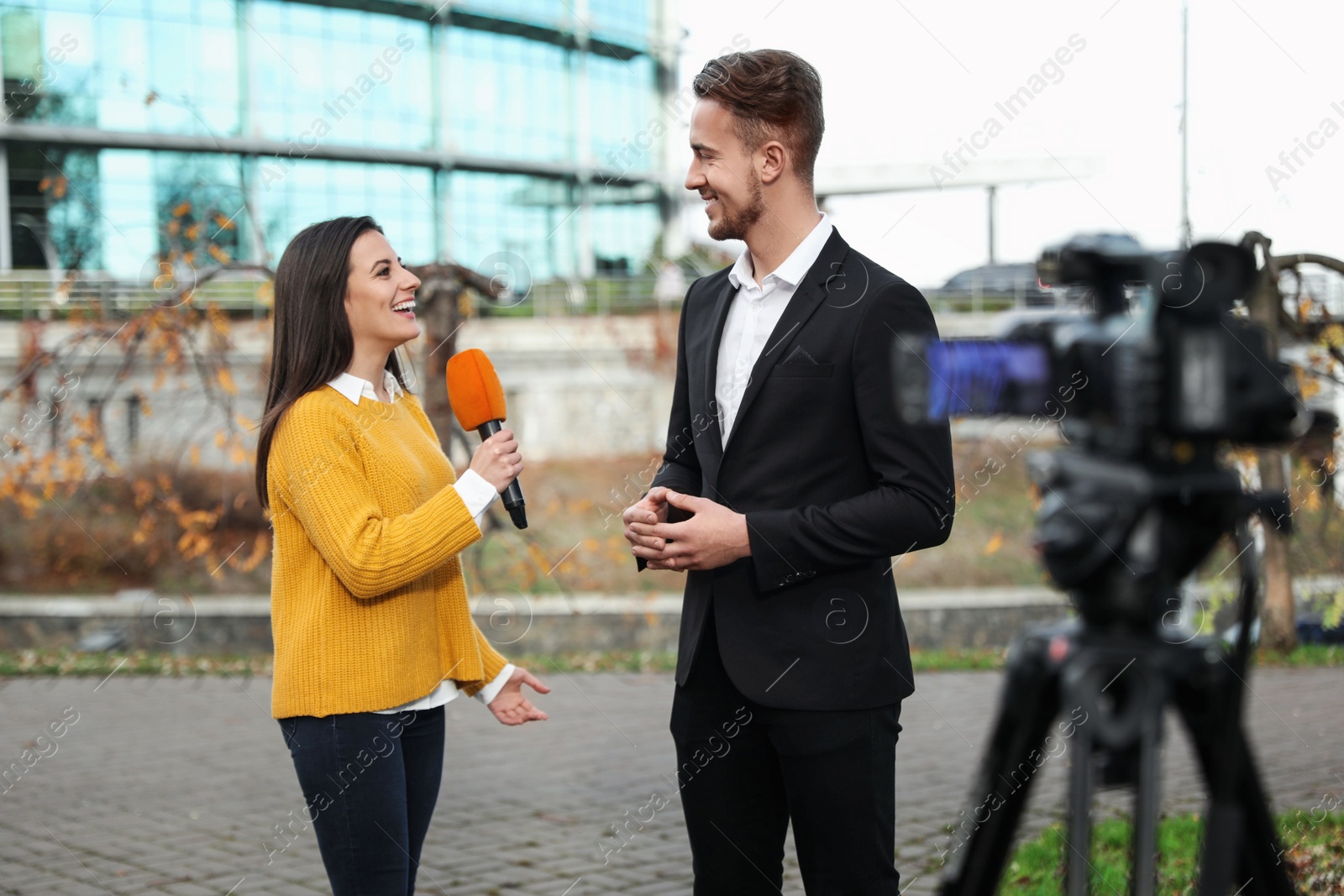 Photo of Young journalist interviewing businessman on city street