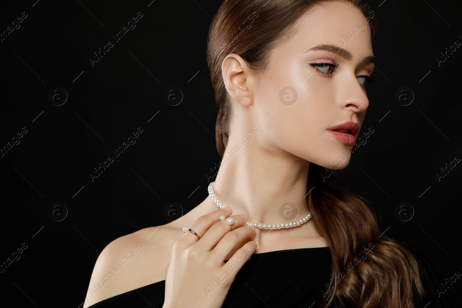 Photo of Young woman wearing elegant pearl jewelry on black background, space for text