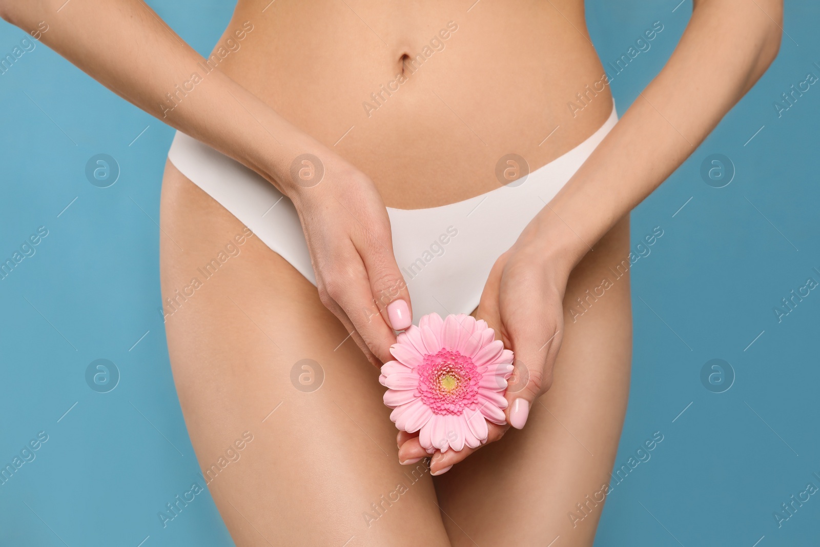 Photo of Woman in white panties with gerbera flower on light blue background, closeup