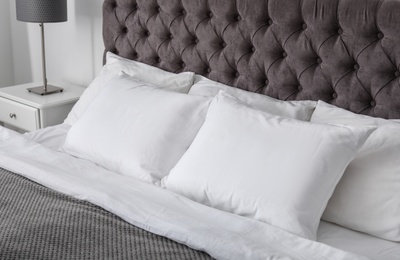 Soft white pillows on comfortable bed indoors