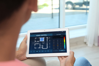 Image of Woman using energy efficiency home control system on tablet, closeup