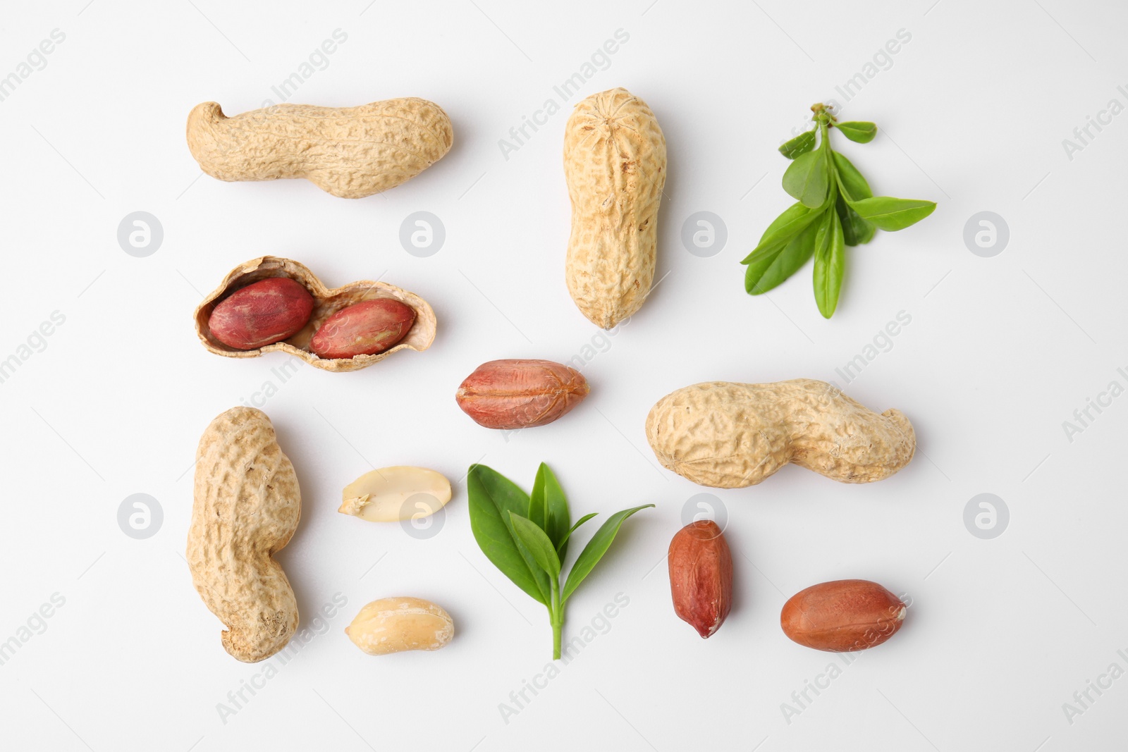 Photo of Fresh peanuts and leaves on white table, flat lay