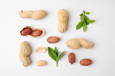 Photo of Fresh peanuts and leaves on white table, flat lay