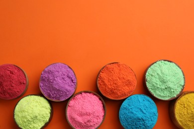 Photo of Colorful powders in bowls on orange background, flat lay with space for text. Holi festival celebration