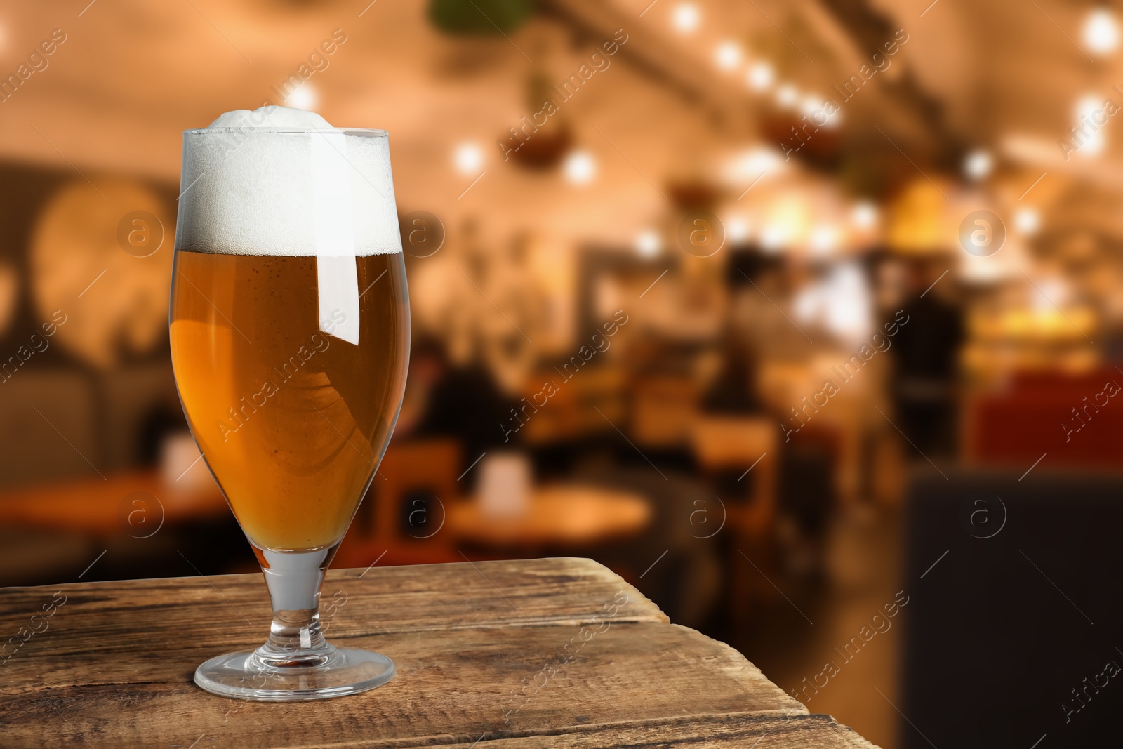 Image of Glass with fresh beer on wooden table in pub, space for text