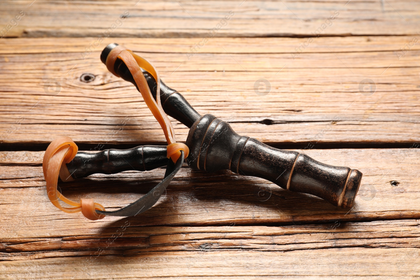 Photo of Black slingshot with leather pouch on wooden table