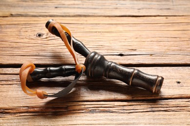 Photo of Black slingshot with leather pouch on wooden table