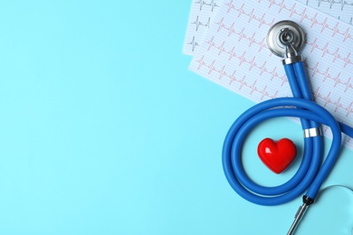 Stethoscope with red heart and cardiogram on blue background, flat lay. Space for text