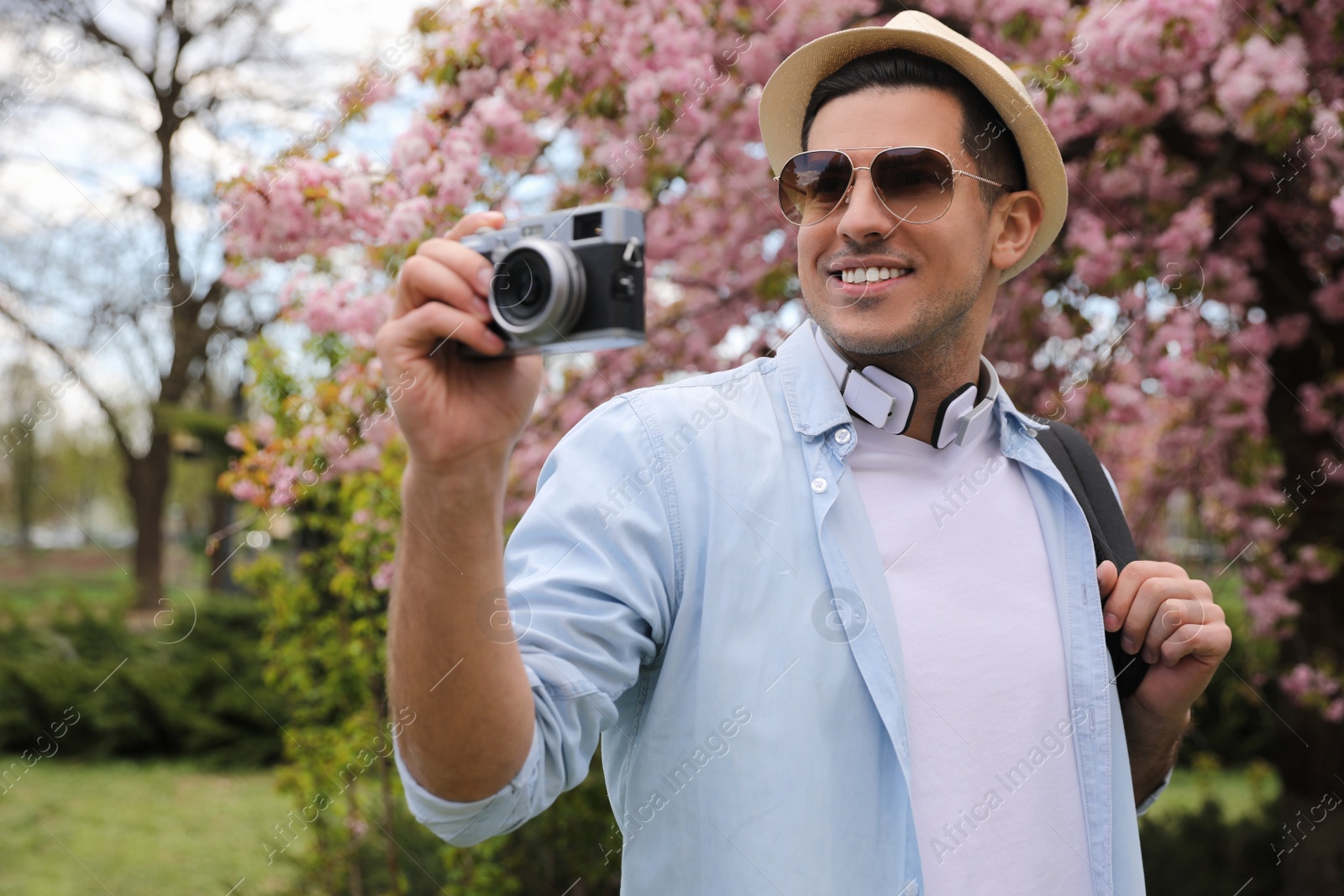 Photo of Happy male tourist with camera in park on spring day