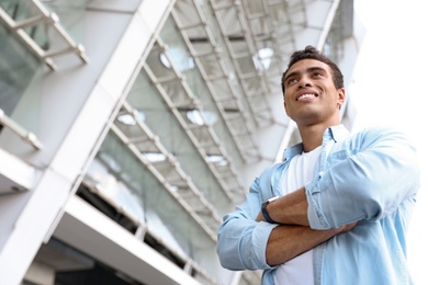 Portrait of handsome young African-American man on city street, low angle view. Space for text