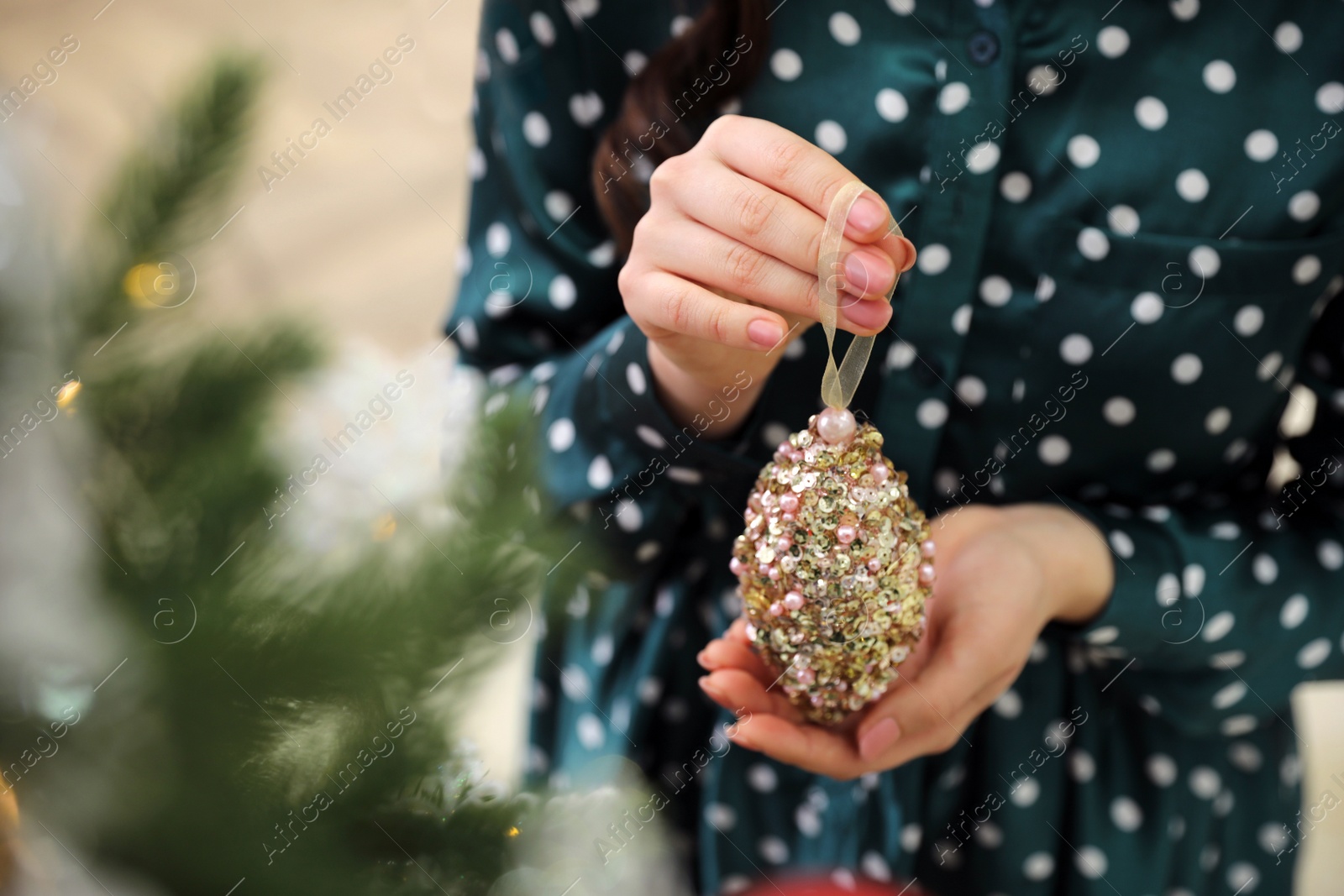 Photo of Woman decorating Christmas tree at home, closeup