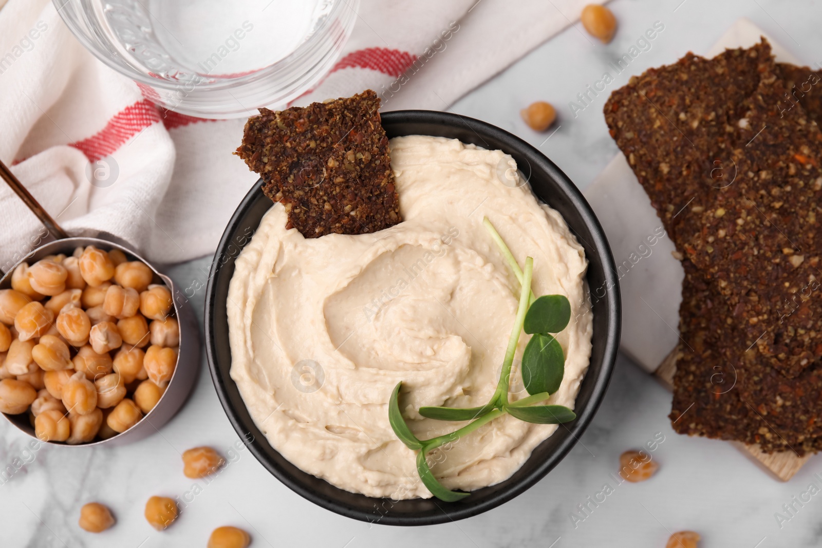 Photo of Delicious hummus with crispbread served on white marble table, flat lay