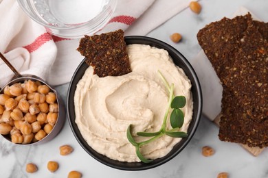 Photo of Delicious hummus with crispbread served on white marble table, flat lay