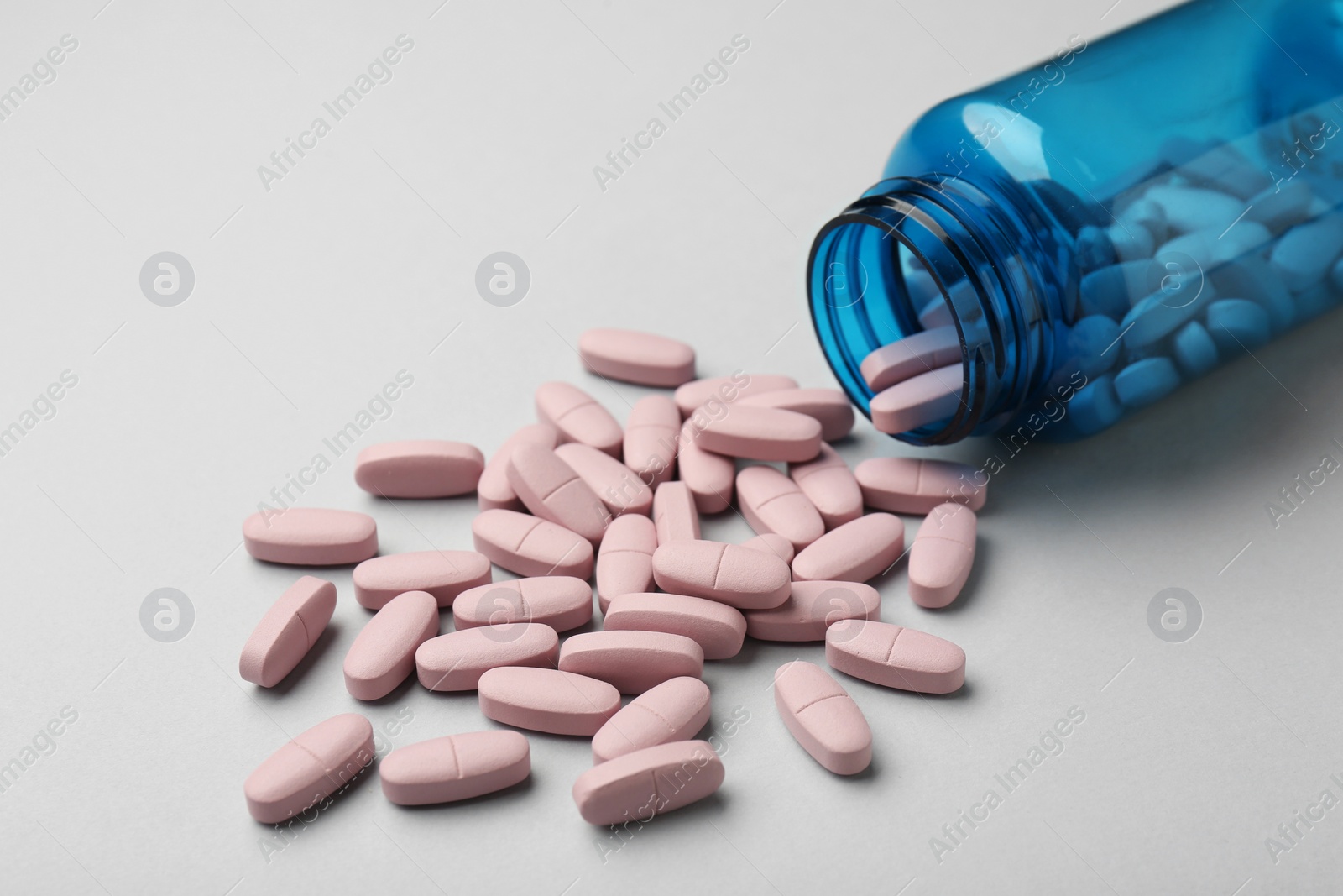 Photo of Vitamin pills and bottle on grey background, closeup