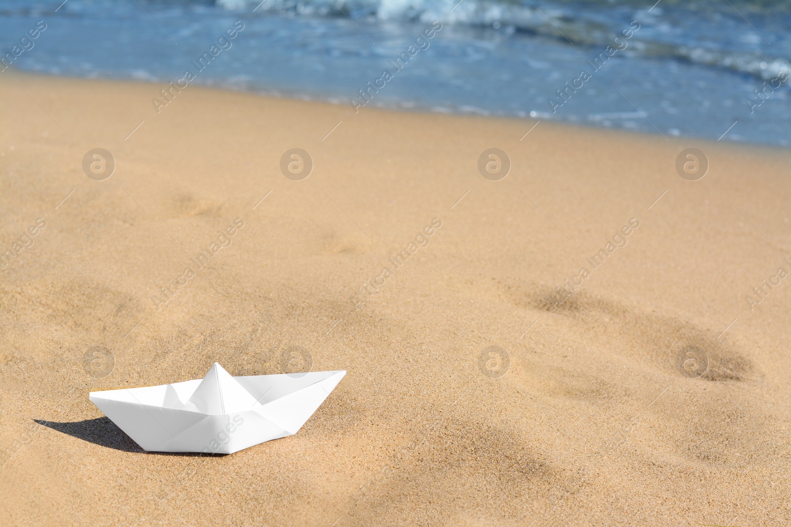 Photo of White paper boat near sea on sunny day, space for text