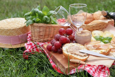 Photo of Picnic blanket with wineglasses and food on green grass