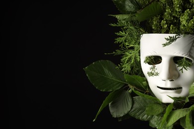 Photo of Theatrical performance. Plastic mask and floral decor on black background, space for text