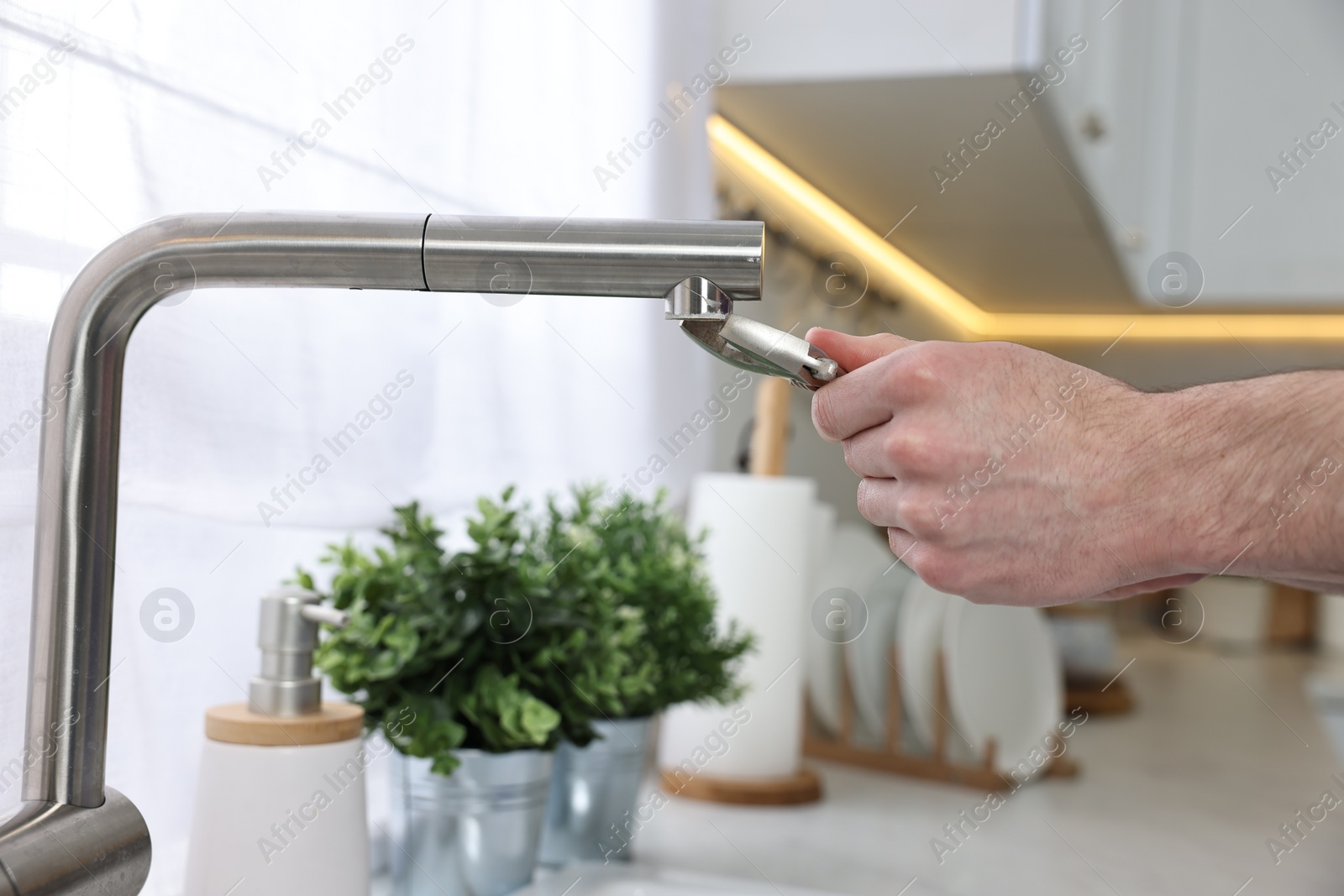 Photo of Plumber repairing faucet with spanner indoors, closeup